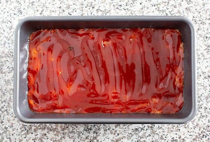 Uncooked meatloaf with ketchup glaze in a loaf pan, ready to bake