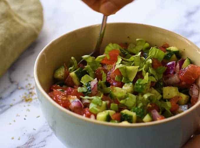 homemade greek vinaigrette with chopped tomatoes, cucumbers, red onion, and basil leaves