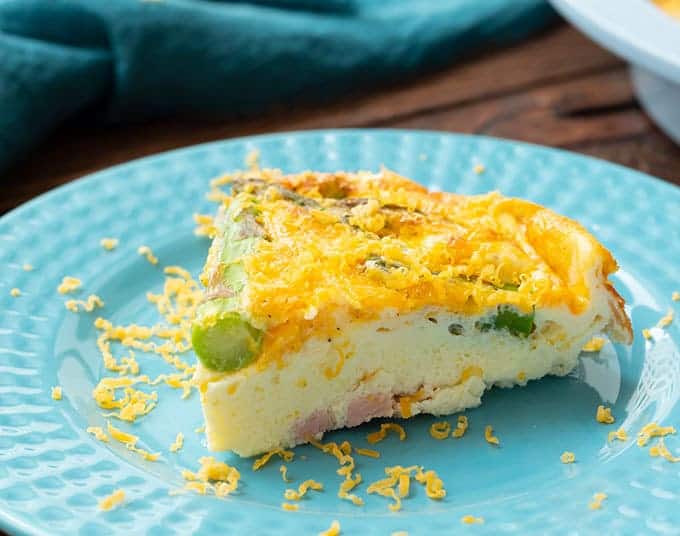 Slice of ham & asparagus quiche on a plate