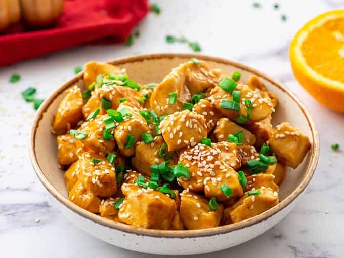 Chinese Mandarin Orange Chicken in a bowl topped with sesame seeds and green onions