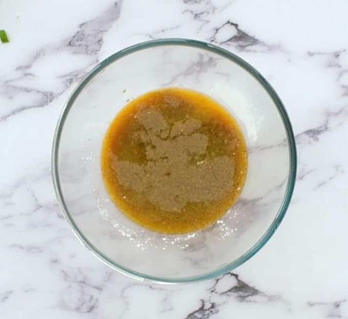 Mixing bowl full of orange juice, soy sauce, brown sugar, corn starch, and pepper for mandarin chicken 