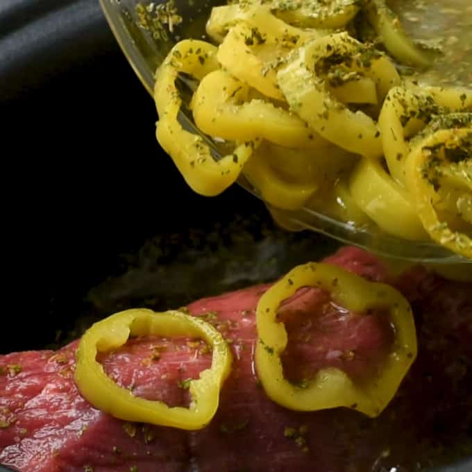 Pouring pepper rings and dressing mix over eye of round roast