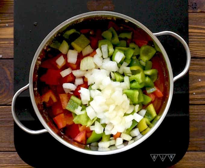 Pot full of ground beef, chopped sweet bell peppers, chopped onion, diced tomatoes, tomato sauce, garlic, brown sugar, salt, and pepper for a stuffed pepper soup recipe