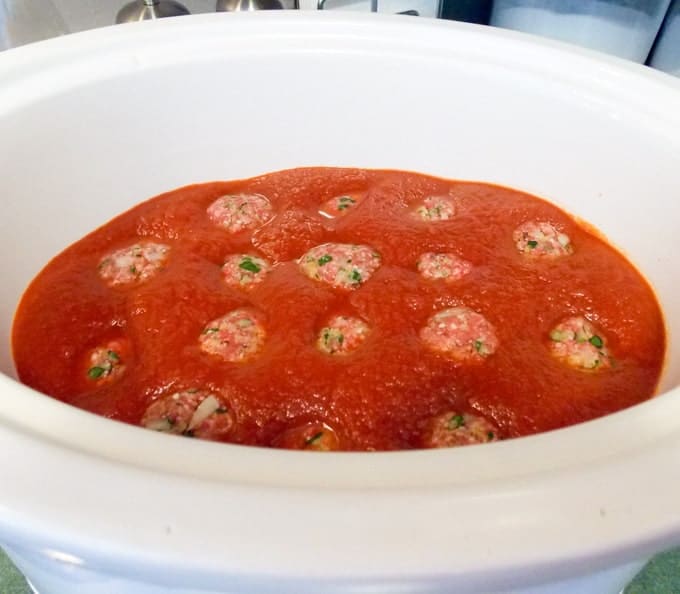 uncooked meatballs and sauce in a crock pot