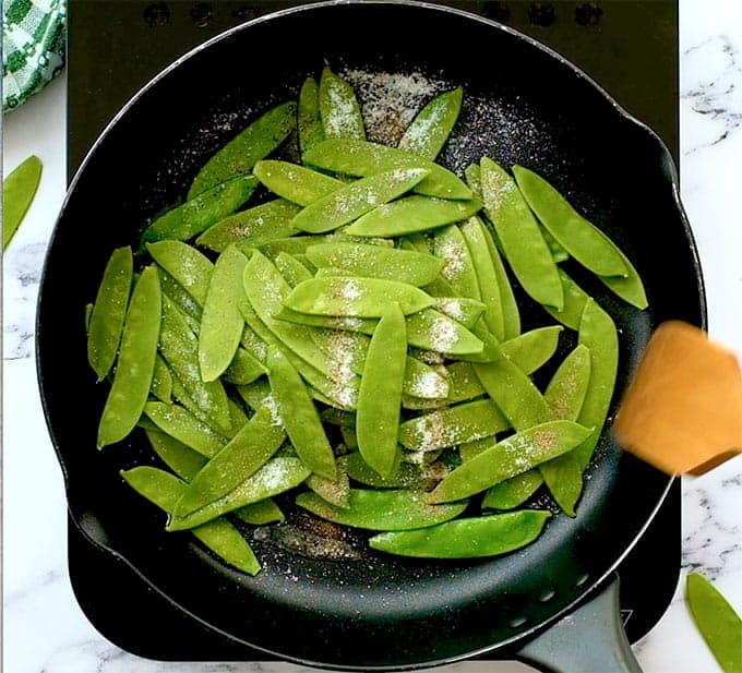 Sugar snap peas in a sautée pan with oil, salt, and pepper