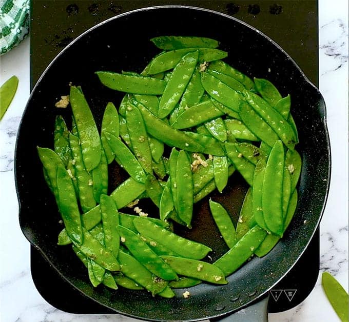 sautéed sugar snap peas with garlic in a skillet