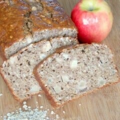 apple cinnamon oatmeal bread sliced on a cutting board with an apple and oats