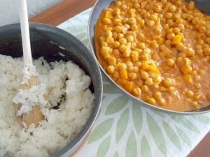 skillet full of coconut curry garbanzo beans next to a pot of cooked white rice