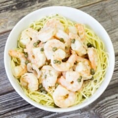 Shrimp Piccata over pasta in a white bowl