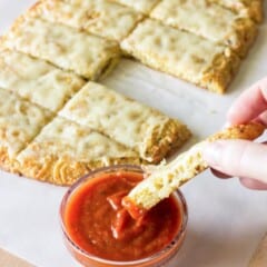 piece of Quinoa Crust Cheesy Garlic Bread being dipped in marinara sauce