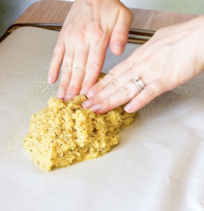 pressing Quinoa Crust dough on a baking sheet