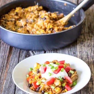 white bowl full of One Pot Chicken Enchilada Bowls with skillet in the background