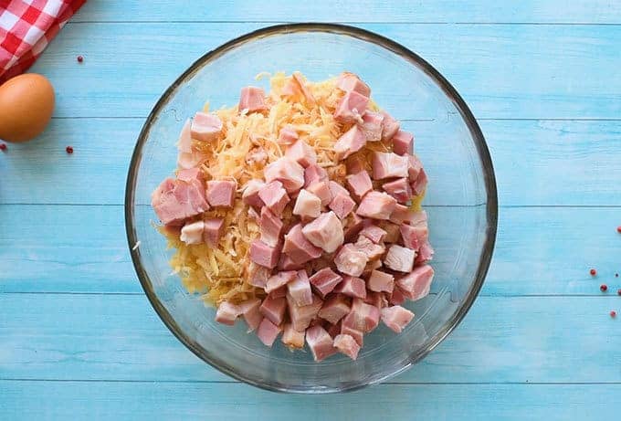 Bowl of frozen hash brown potatoes and chopped ham for easy breakfast casserole