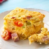 Slice of hash brown breakfast casserole with ham, cheese, and vegetables