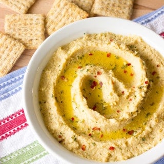 white bowl full of Simple Hummus Without Tahini with crackers on the side