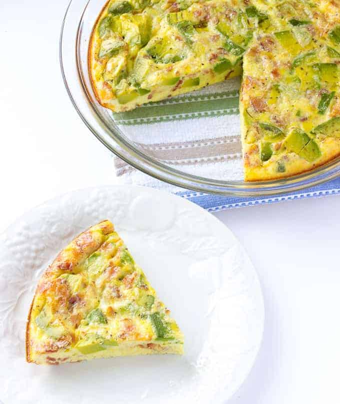 Avocado Bacon Crustless Quiche with one piece taken out and put on a white plate