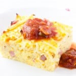 A piece of easy breakfast casserole on a white plate with some salsa