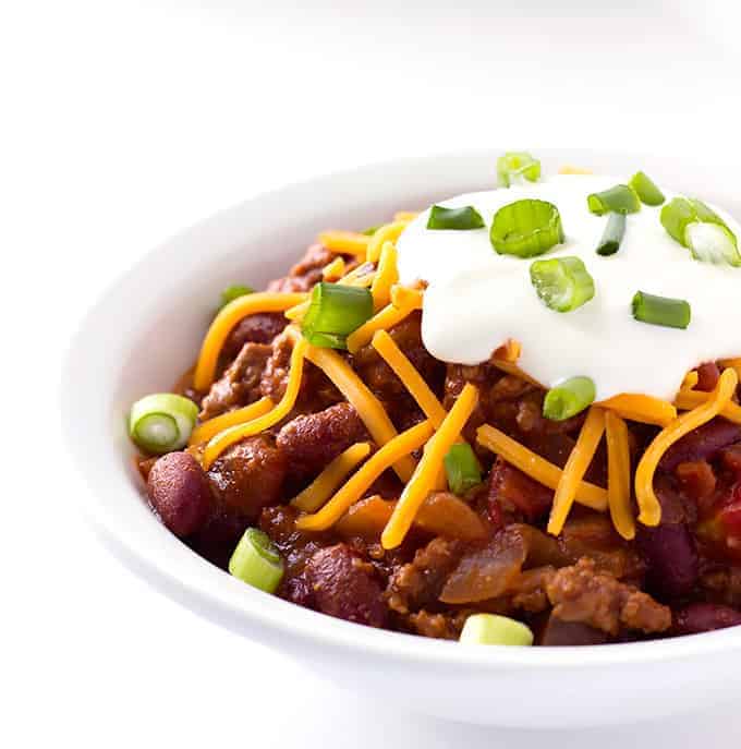 white bowl full of Maple Bourbon Chili with toppings