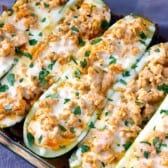 buffalo chicken stuffed zucchini with cheese in a baking dish