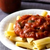 Bowl of pasta topped with spaghetti sauce with mushrooms and zucchini