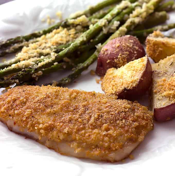 white plate with a Baked Parmesan Pork Chop, Potatoes, & Asparagus