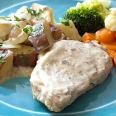 blue plate full of Creamy Crock Pot Pork Chops Potatoes & Onions