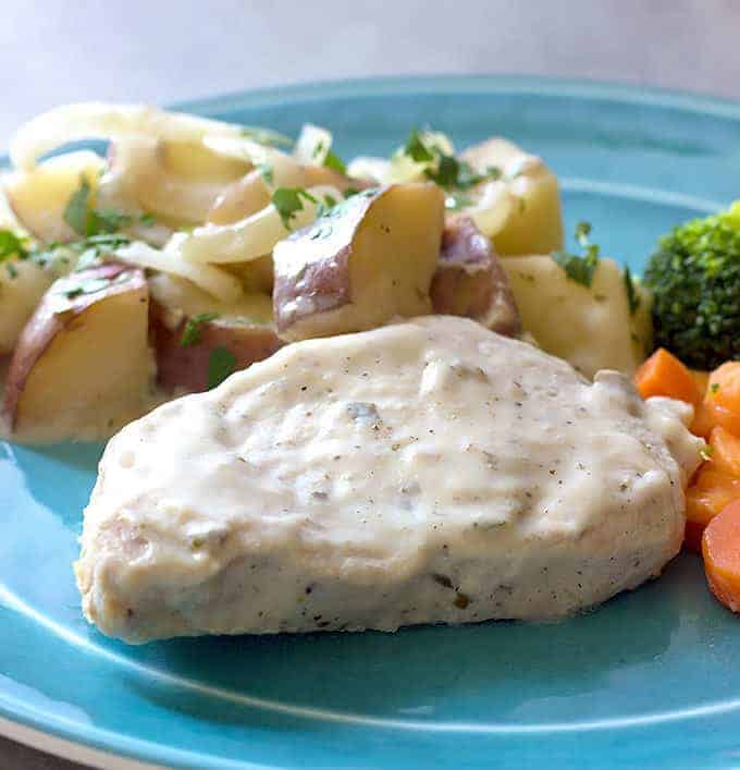 blue plate full of Creamy Crock Pot Pork Chops Potatoes & Onions