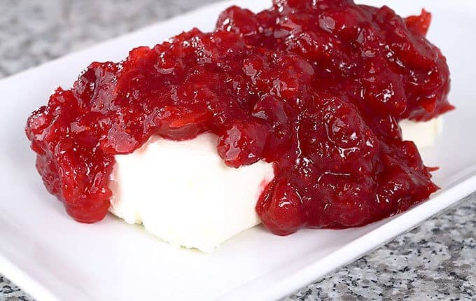 Cranberry sauce poured over cream cheese on a white plate