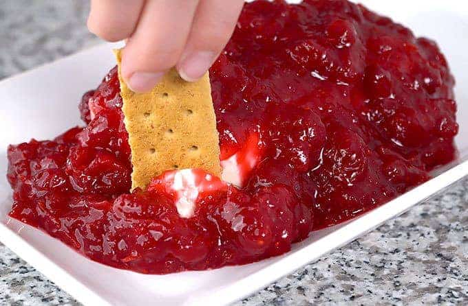 cranberry cream cheese dip with graham cracker being dipped into it
