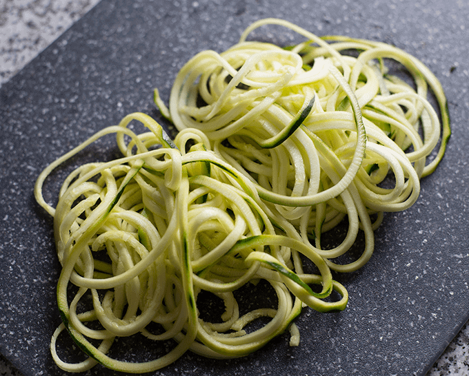 zucchini noodles on a dark grey cutting board