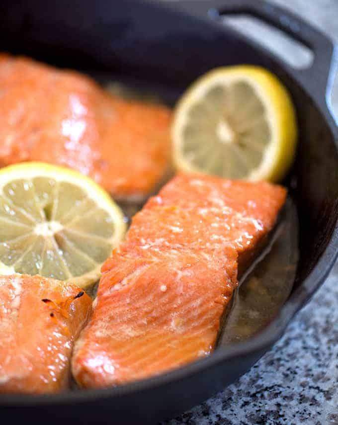 Cooked salmon in a cast iron skillet with lemon slices