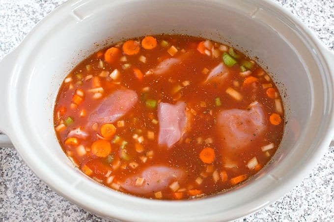 chopped veggies and chicken in an Italian broth in a slow cooker