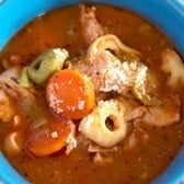 blue bowl full of italian chicken tortellini soup