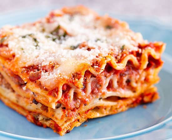 Slice of the best classic lasagna recipe with layers of pasta, homemade meat sauce, ricotta mozzarella and parmesan cheese