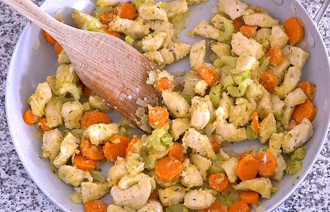 Stirring flour into butter, chicken, and vegetables