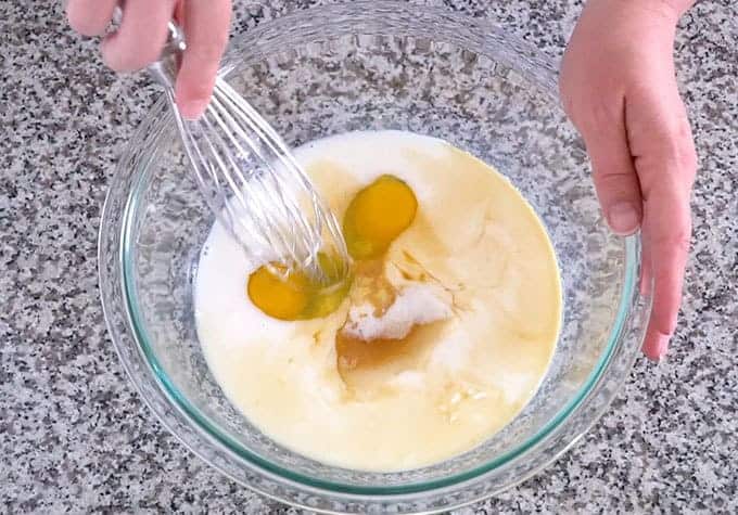 A mixing bowl with milk, sour cream, sugar, eggs, and vanilla for the best pancake recipe