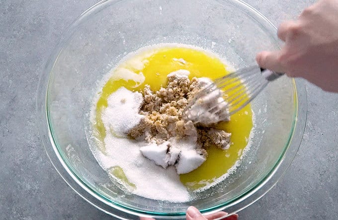 Melted butter, brown sugar, and sugar in a mixing bowl to make chocolate chip cookies from scratch