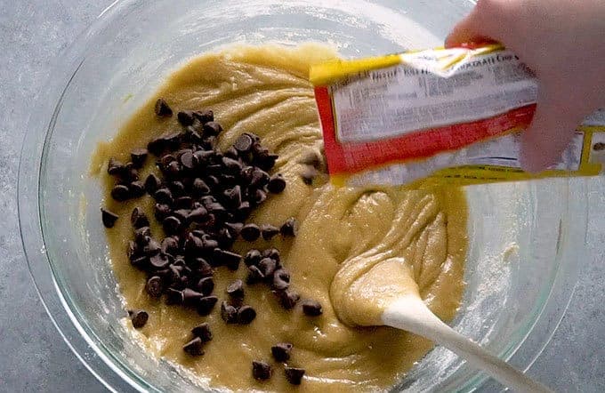 Chocolate chips being poured into batter for easy chocolate chip cookies