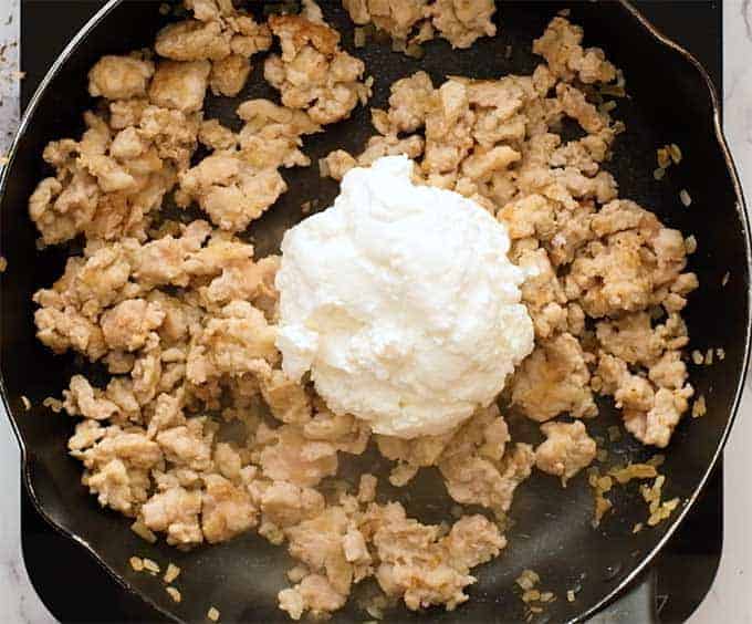 Skillet full of Italian sausage and ricotta cheese 