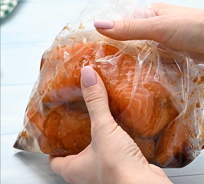 plastic storage bag with salmon filets and teriyaki marinade inside