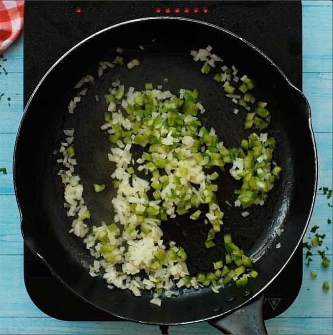 skillet with olive oil, diced onions, and diced green peppers sautéing.