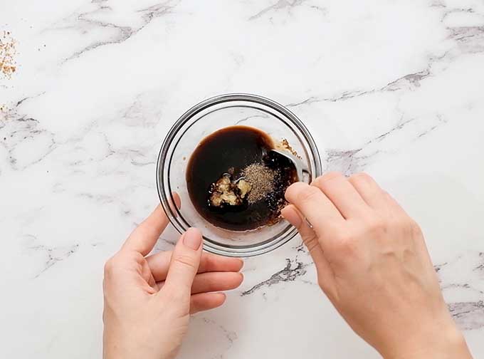 glass bowl full of teriyaki marinade being stirred with a spoon