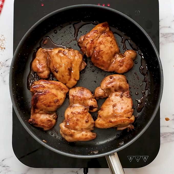 cooked chicken thighs coated in teriyaki glaze in a large skillet