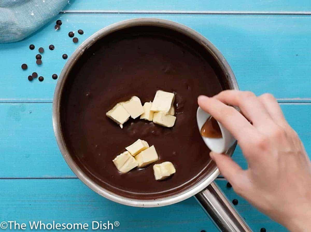butter and vanilla being added to a pot with chocolate pudding