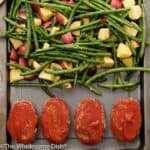 4 mini meatloafs topped with ketchup on a baking sheet with potatoes and green beans
