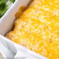 Dish of baked sour cream chicken enchiladas covered in melted cheese
