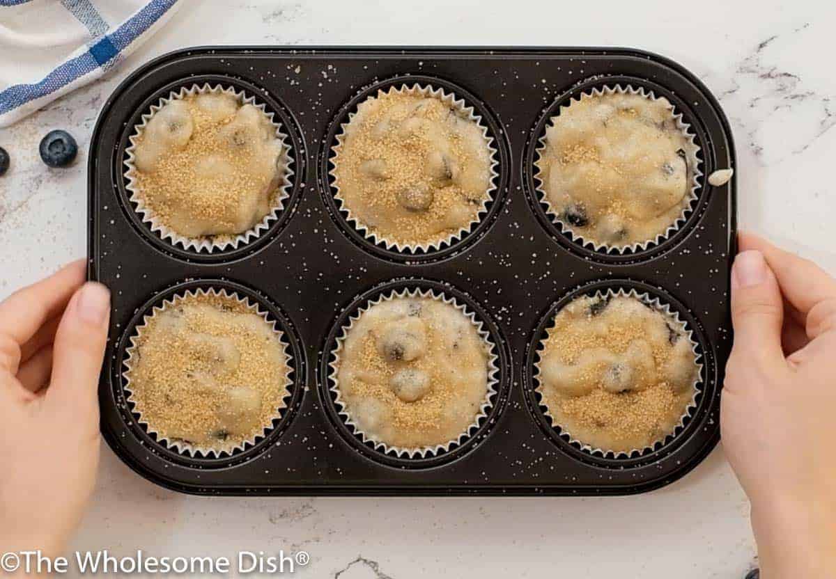 Muffin tin full of blueberry muffin batter.