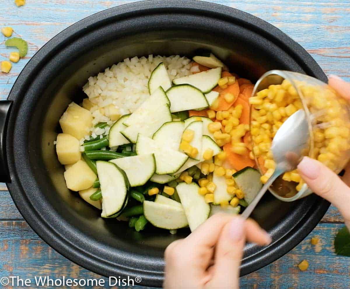 Adding celery, carrots, zucchini, and corn to the crock pot.