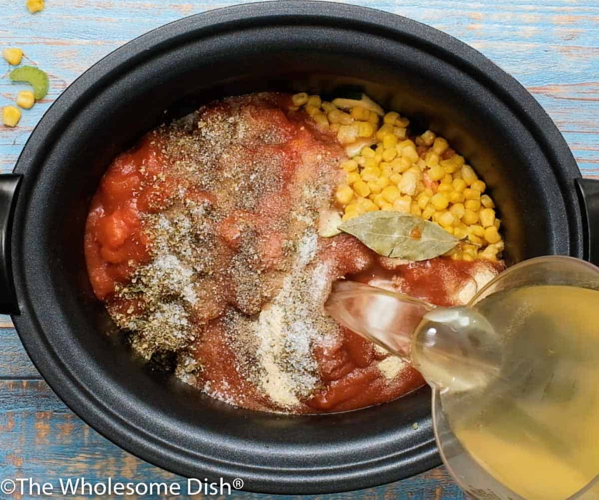 Adding tomato sauce, diced tomatoes, broth , and seasonings to the crock pot.