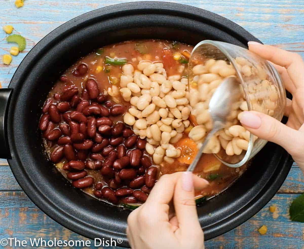 Adding red and white beans to the crock pot.